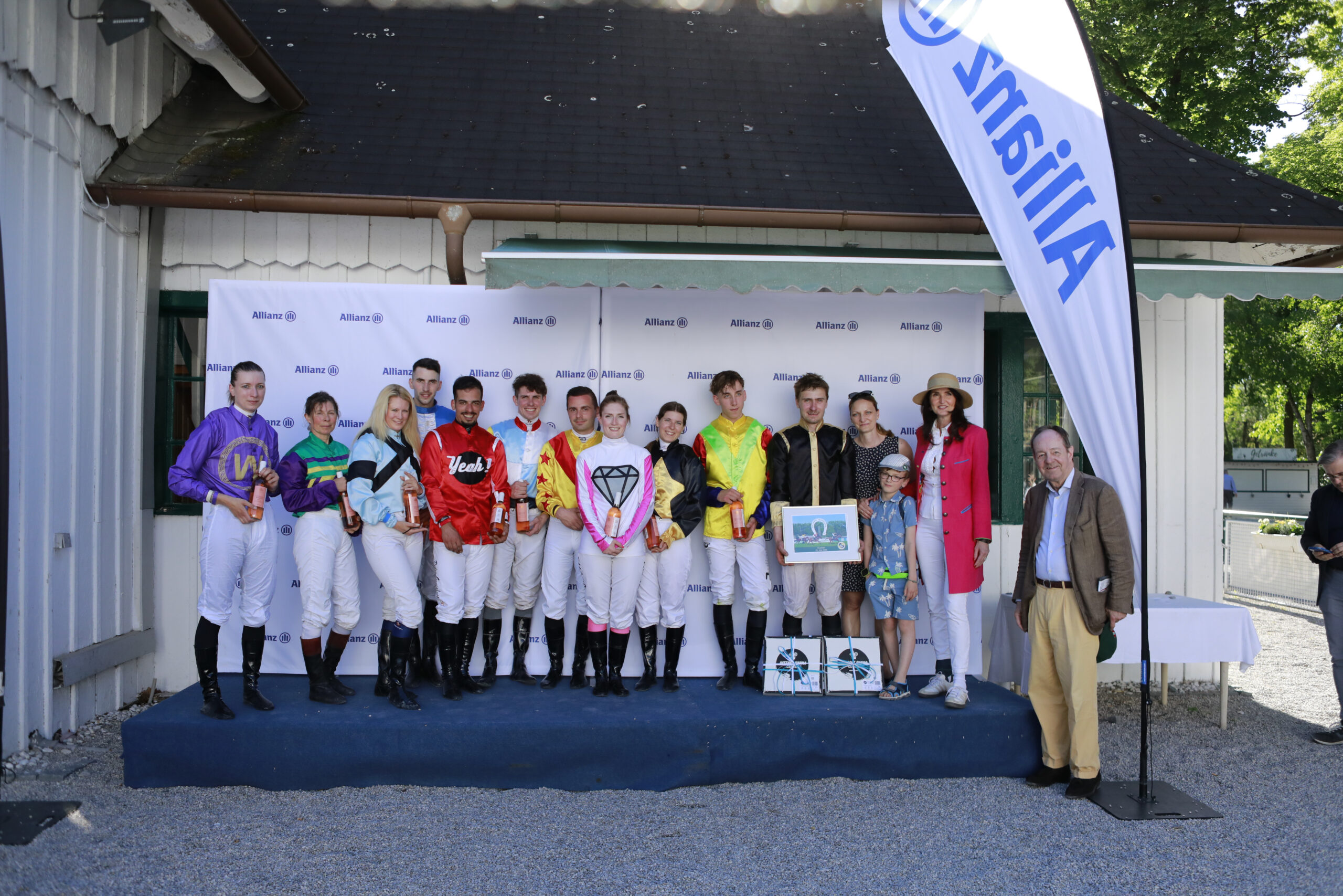 23.05.2026 - Munich; Winners presentation with Swen Strassmeier (right) after winning the Gemeinsam stark - Preis der Partnerschaft zwischen Allianz und MRV with Superjet at Munich-Racecourse/Germany. Jaqueline Laquai, Birgit Roesch, Claudia Fleissner, Zan Sovan, Jose Pedro Martins Goncalves, Matthew Sebastian Johnson, Kevin Braye, Shannon Spratter, Jaqueline Nuetzl, Julian Sixt, Swen Strassmeier, Andrea Schneider (President Bayerische Vereinigung der Amateur-Rennreiter e.V.), Felix Schneider, representative of the sponsor, Freiherr Dr. Georg von Gumppenberg (Chairman Muenchener Rennverein e.V.) have lined up for a group photo to celebrate his victory. Credit: Lajos-Eric Balogh/turfstock.com